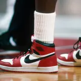 Ein Paar ikonische Air Jordan 1 Sneaker in Rot und Weiß, vielleicht der teuerste Schuh der Welt, auf einem Basketballplatz.