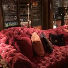 Luxuriöses rotes Samtsofa im Hans Zimmer Studio, umgeben von Musik-Equipment und Gitarren.