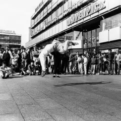 Junge Leute versammeln sich, um einer Breakdance-Performance zuzusehen, die an die Energie von Hip-Hop-Bands erinnert.