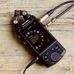 TASCAM Portacapture X8 mit angeschlossenen Mikrofonen auf Holzoberfläche. Ideal für Mehrspuraufnahmen.