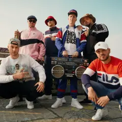 Sechs Männer in Hip-Hop-Kleidung mit einer Boombox. Sie zeigen, was ist rap: ein Lebensgefühl, Musik und Style.