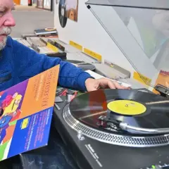 Mann wählt eine DDR-Schallplatte aus, um sie als DJ aufzulegen.