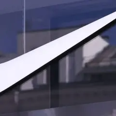 Das ikonische Nike-Logo, ein Symbol für die Nike Logo Entwicklung, leuchtet weiß vor einem blauen Himmel und reflektiert Gebäude.