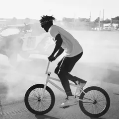 Nigel Sylvester fährt BMX, während im Hintergrund ein Buggy im Rauch steht.