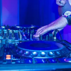 DJ-Pult im blauen Licht, Hand am Regler für einen perfekten dj mix.