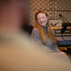 Simon Triebel lacht herzlich in einem Aufnahmestudio, bereit für ein Interview.