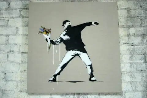 Ein Mann wirft Blumen statt eines Molotowcocktails. Das ist typisch für Banksy, der mit seiner Kunst zum Nachdenken anregt.