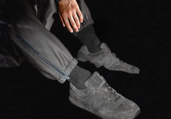 Graue Stone Island Ultras Sneaker mit Reißverschluss an der Hose.