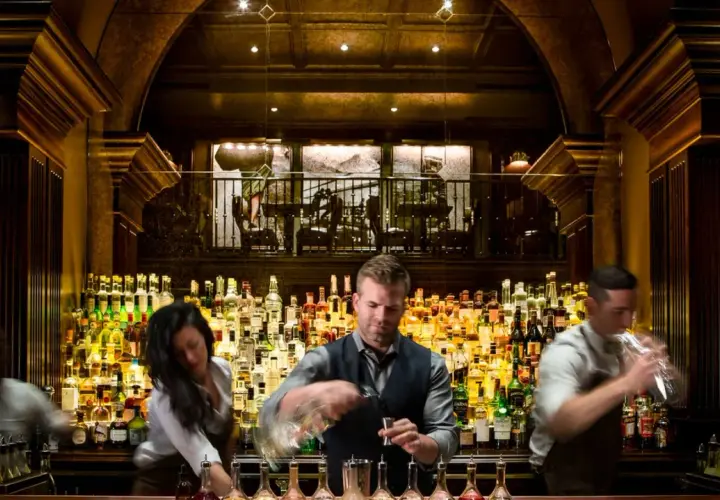 Bartender mixt Drinks hinter einer riesigen Auswahl an Flaschen. Hier gibt es die besten Kollegah Lines für jeden Geschmack.