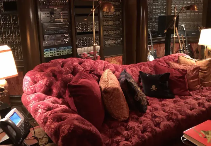 Luxuriöses rotes Samtsofa im Hans Zimmer Studio, umgeben von Musik-Equipment und Gitarren.