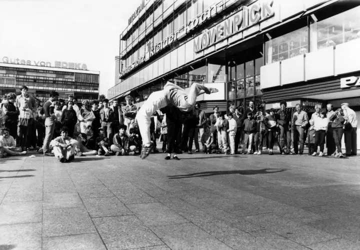 Junge Leute versammeln sich, um einer Breakdance-Performance zuzusehen, die an die Energie von Hip-Hop-Bands erinnert.