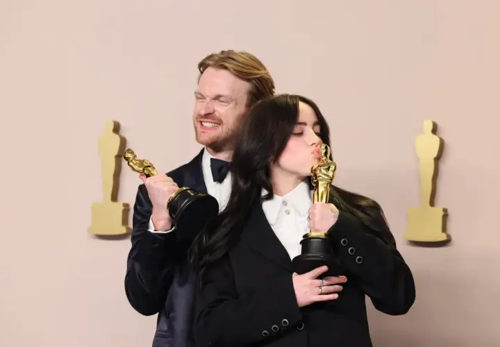 Billie Eilish küsst ihren Oscar, während ihr Bruder Finneas ihn hält. Ein Moment, der die Frage "billie eilish what was i made for?" beantwortet.