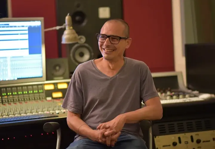 Moses Schneider, lächelnd in einem Tonstudio, sitzt vor einem Mischpult und einem Computerbildschirm.