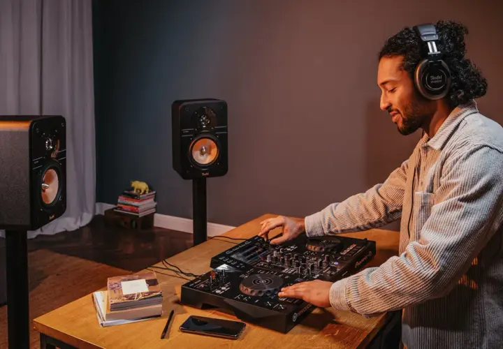 Mann mit Kopfhörern legt Musik auf, um einen DJ-Set aufzunehmen. Zwei Lautsprecher stehen bereit.