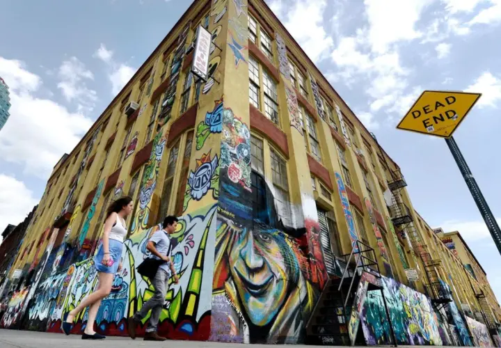 Buntes Graffiti ziert ein gelbes Gebäude in New York. Ein "Dead End"-Schild weist auf die kreative Sackgasse hin.