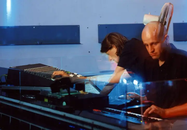 Robert Henke und Kollegin im Studio, umgeben von blauem Licht und Musik-Equipment.