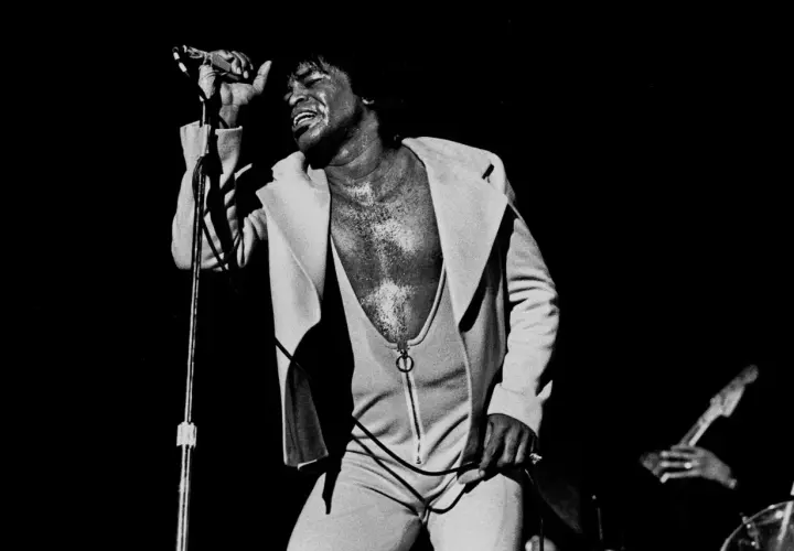 James Brown singt mit geschlossenen Augen und erhobener Hand, ein ikonisches Bild, das an bekannte Funk-Songs erinnert.