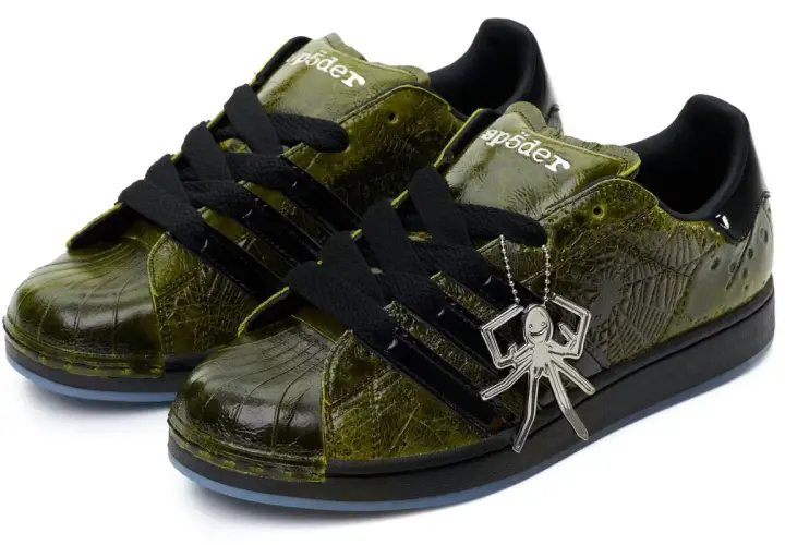 Grüne Adidas Superstar Sneaker mit Spinnennetz-Muster und Spinnen-Anhänger. Ein Highlight der Adidas Kollaborationen.