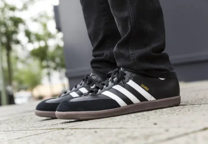 Schwarze Adidas Samba Sneaker mit brauner Gummisohle und weißen Streifen. Sie fallen größengerecht aus und passen gut zu Jeans.