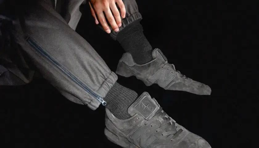 Graue Stone Island Ultras Sneaker mit Reißverschluss an der Hose.