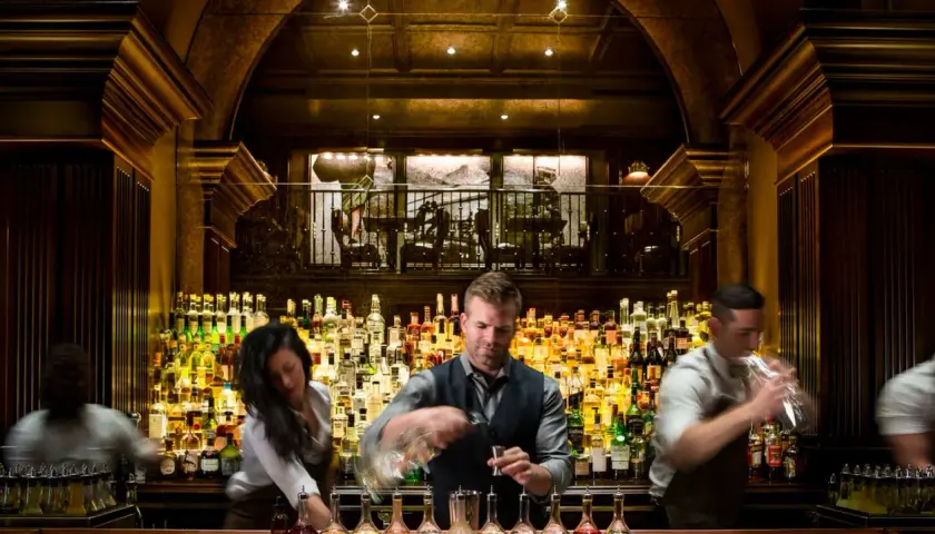 Bartender mixt Drinks hinter einer riesigen Auswahl an Flaschen. Hier gibt es die besten Kollegah Lines für jeden Geschmack.