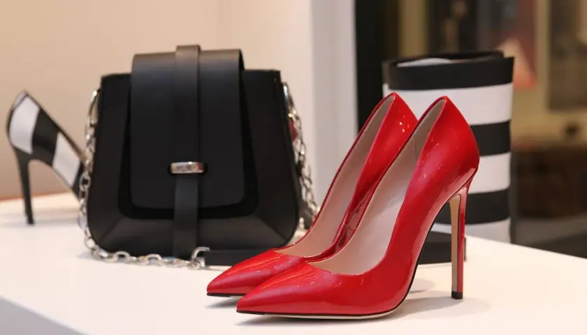 Glänzende rote Pumps und eine schwarze Tasche, die die teuersten Schuhe der Welt für Damen repräsentieren könnten.