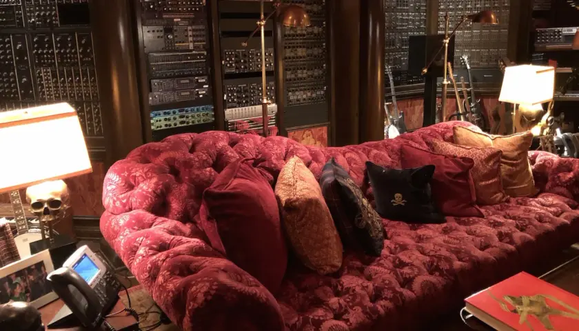 Luxuriöses rotes Samtsofa im Hans Zimmer Studio, umgeben von Musik-Equipment und Gitarren.