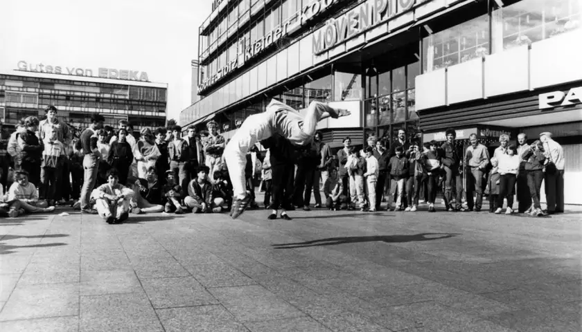 Junge Leute versammeln sich, um einer Breakdance-Performance zuzusehen, die an die Energie von Hip-Hop-Bands erinnert.
