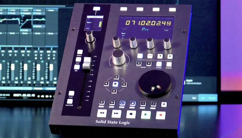Solid State Logic UC1 Mischpult mit digitalen Fader-Anzeigen und Drehreglern. Im Hintergrund sind DAW-Fenster zu sehen.
