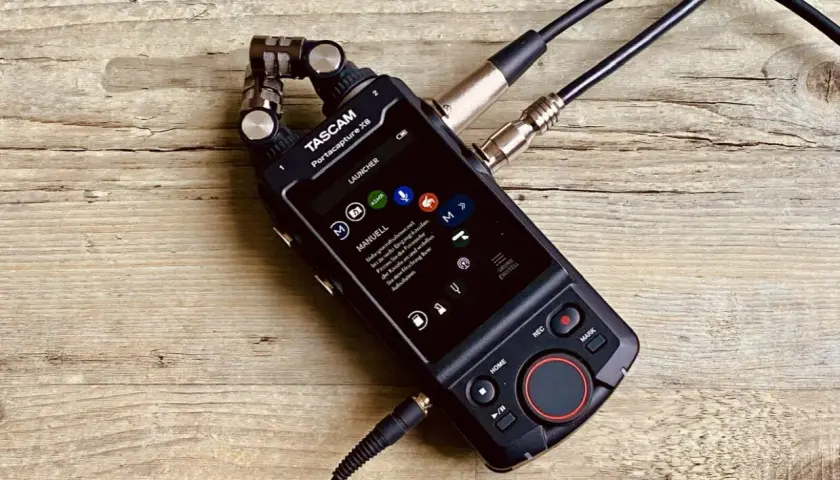 TASCAM Portacapture X8 mit angeschlossenen Mikrofonen auf Holzoberfläche. Ideal für Mehrspuraufnahmen.