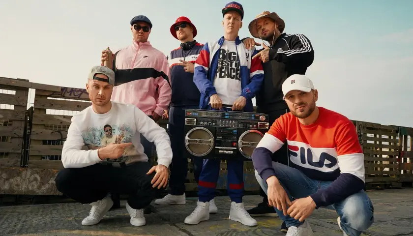 Sechs Männer in Hip-Hop-Kleidung mit einer Boombox. Sie zeigen, was ist rap: ein Lebensgefühl, Musik und Style.