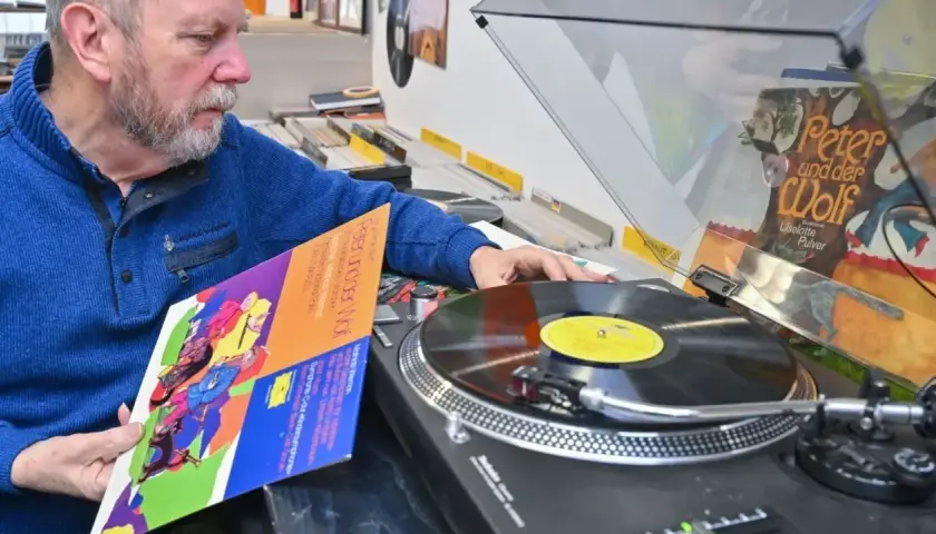 Mann wählt eine DDR-Schallplatte aus, um sie als DJ aufzulegen.