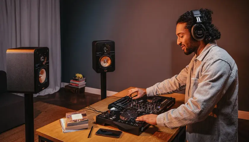 Mann mit Kopfhörern legt Musik auf, um einen DJ-Set aufzunehmen. Zwei Lautsprecher stehen bereit.