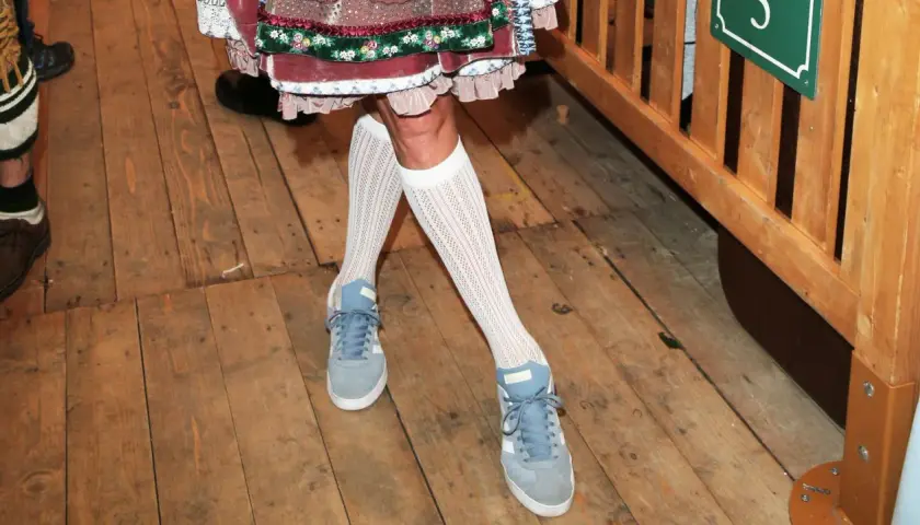 Moderne Sneaker zur traditionellen Lederhose, ein unerwarteter, aber stylischer Mix. Weiße Netzstrümpfe runden den Look ab.