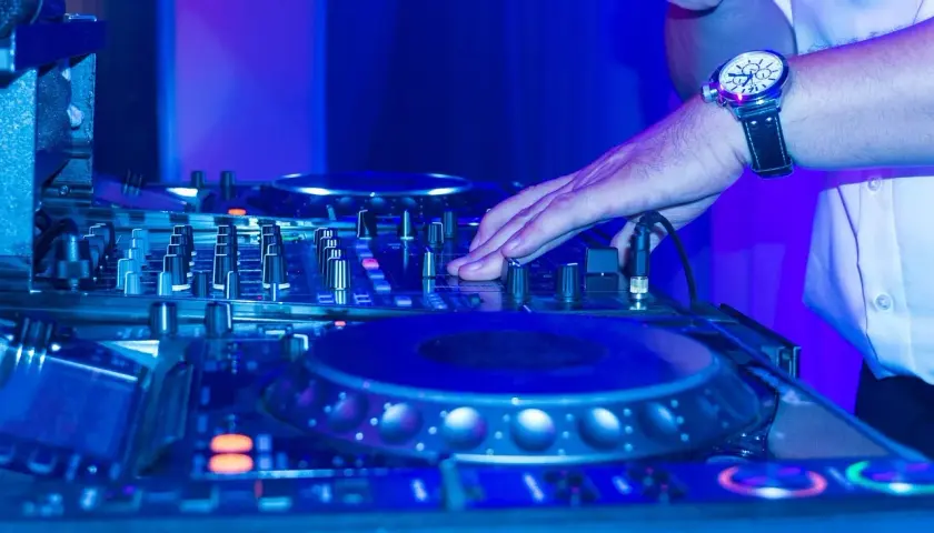 DJ-Pult im blauen Licht, Hand am Regler für einen perfekten dj mix.