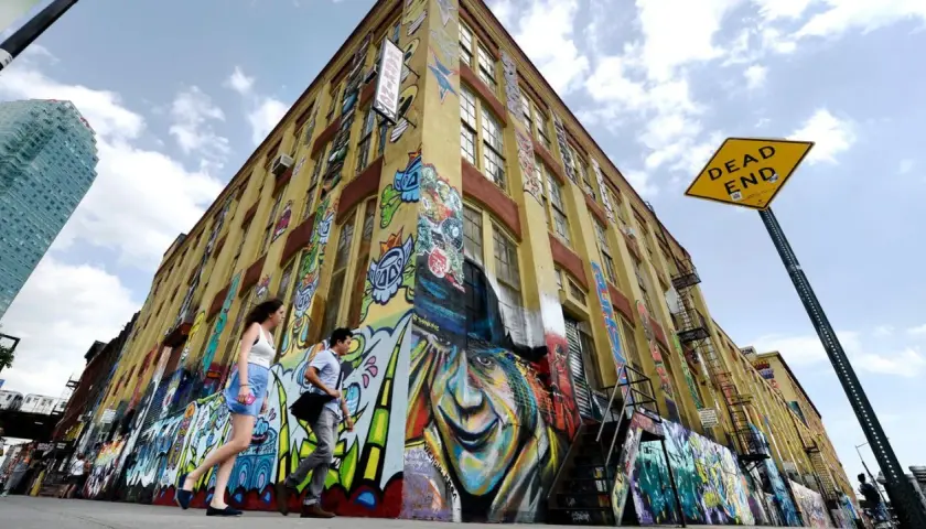 Buntes Graffiti ziert ein gelbes Gebäude in New York. Ein "Dead End"-Schild weist auf die kreative Sackgasse hin.