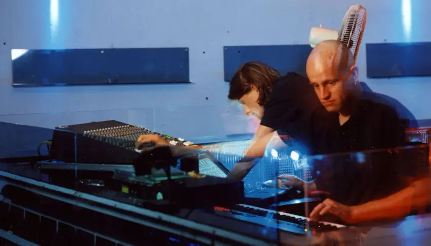 Robert Henke und Kollegin im Studio, umgeben von blauem Licht und Musik-Equipment.