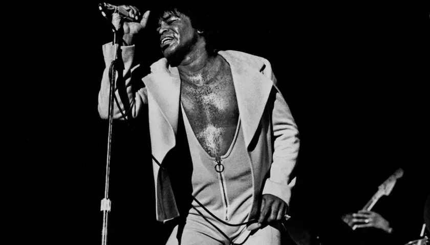 James Brown singt mit geschlossenen Augen und erhobener Hand, ein ikonisches Bild, das an bekannte Funk-Songs erinnert.