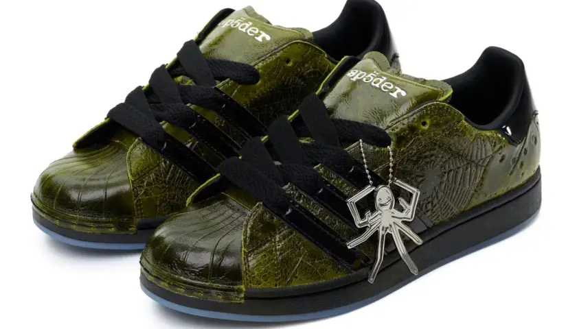 Grüne Adidas Superstar Sneaker mit Spinnennetz-Muster und Spinnen-Anhänger. Ein Highlight der Adidas Kollaborationen.