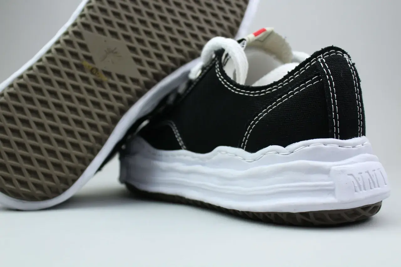 Schwarze Sneaker mit weißer Sohle und Nähten, typisch für japanische Sneaker Marken.
