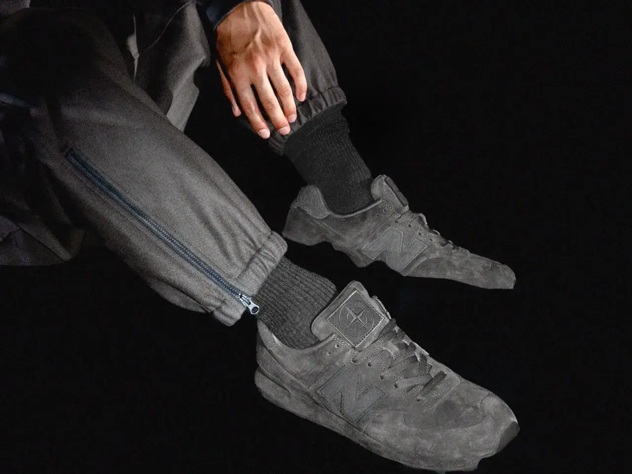 Graue Stone Island Ultras Sneaker mit Reißverschluss an der Hose.
