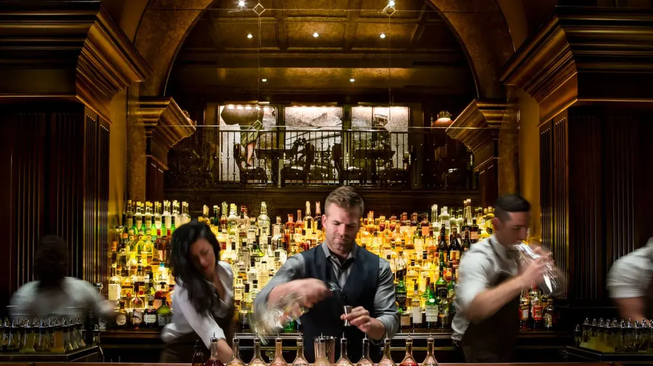 Bartender mixt Drinks hinter einer riesigen Auswahl an Flaschen. Hier gibt es die besten Kollegah Lines für jeden Geschmack.