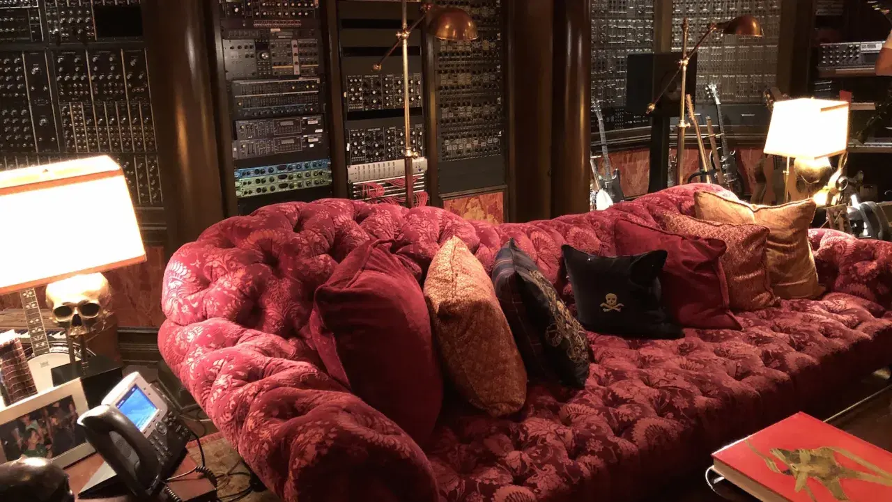 Luxuriöses rotes Samtsofa im Hans Zimmer Studio, umgeben von Musik-Equipment und Gitarren.