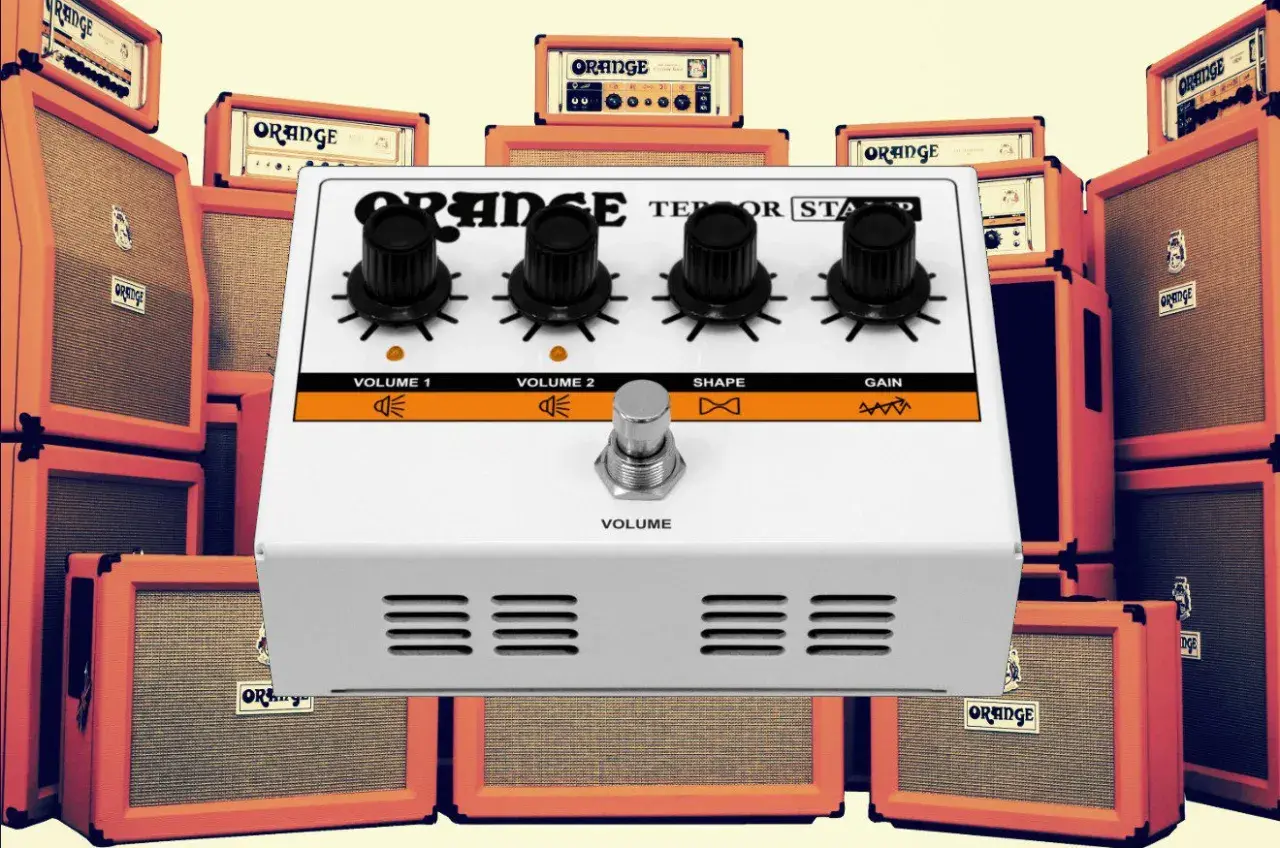 Ein Orange Terror Stamp Pedal steht im Vordergrund, umgeben von vielen Orange Verstärkern.