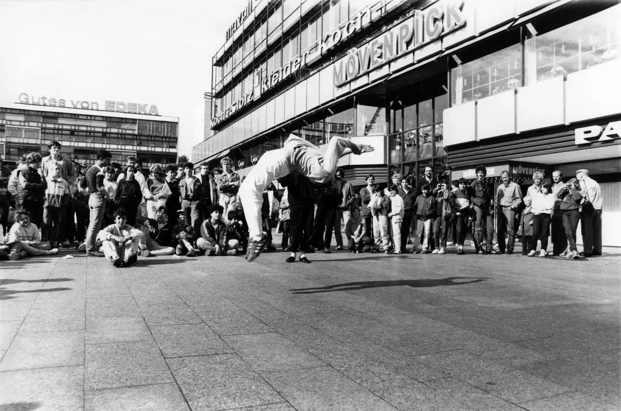 Junge Leute versammeln sich, um einer Breakdance-Performance zuzusehen, die an die Energie von Hip-Hop-Bands erinnert.