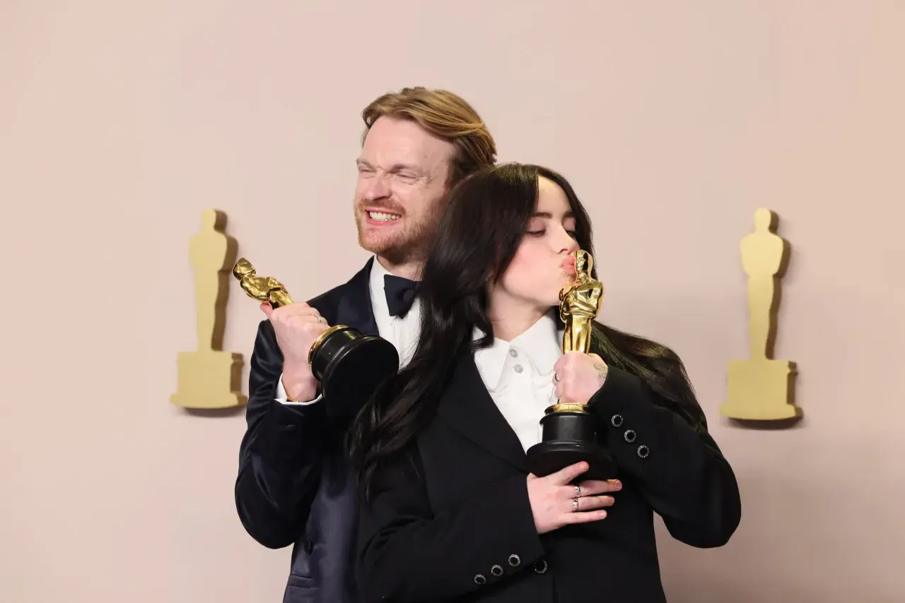 Billie Eilish küsst ihren Oscar, während ihr Bruder Finneas ihn hält. Ein Moment, der die Frage "billie eilish what was i made for?" beantwortet.
