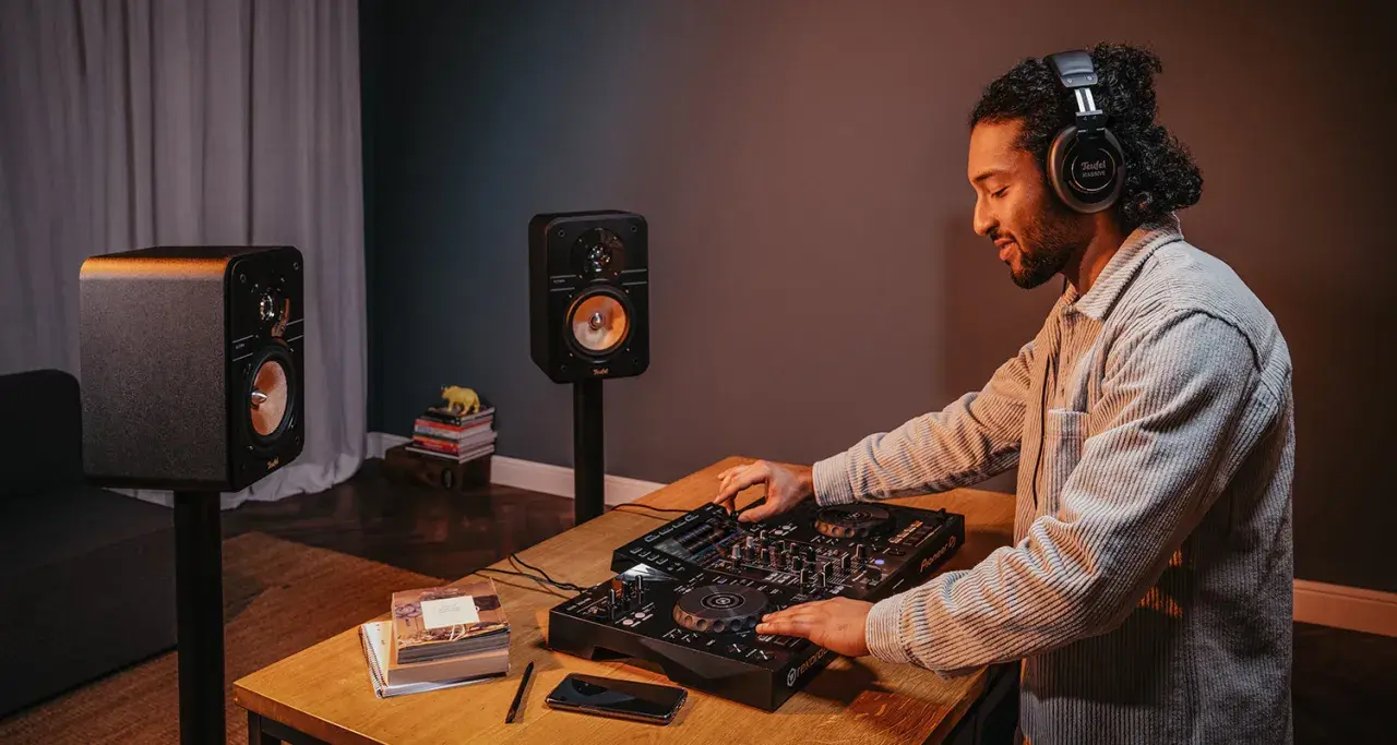 Mann mit Kopfhörern legt Musik auf, um einen DJ-Set aufzunehmen. Zwei Lautsprecher stehen bereit.