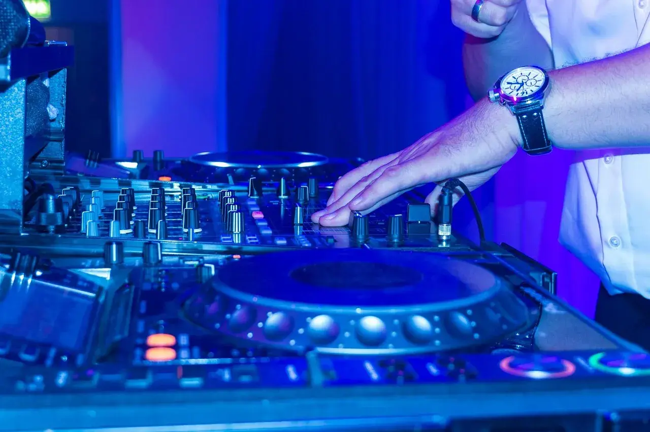 DJ-Pult im blauen Licht, Hand am Regler für einen perfekten dj mix.