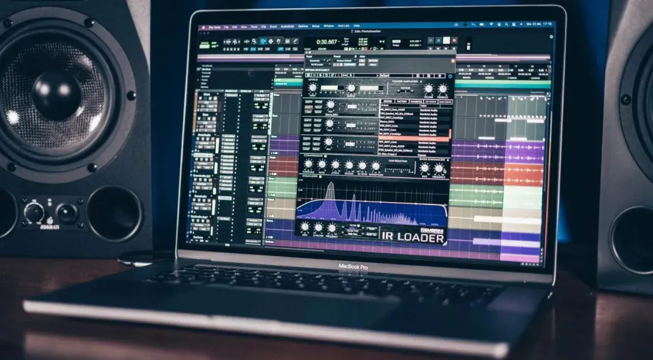 Ein MacBook Pro zeigt eine Musikproduktionssoftware mit einem IR Loader-Plugin, umgeben von Studio-Monitoren.