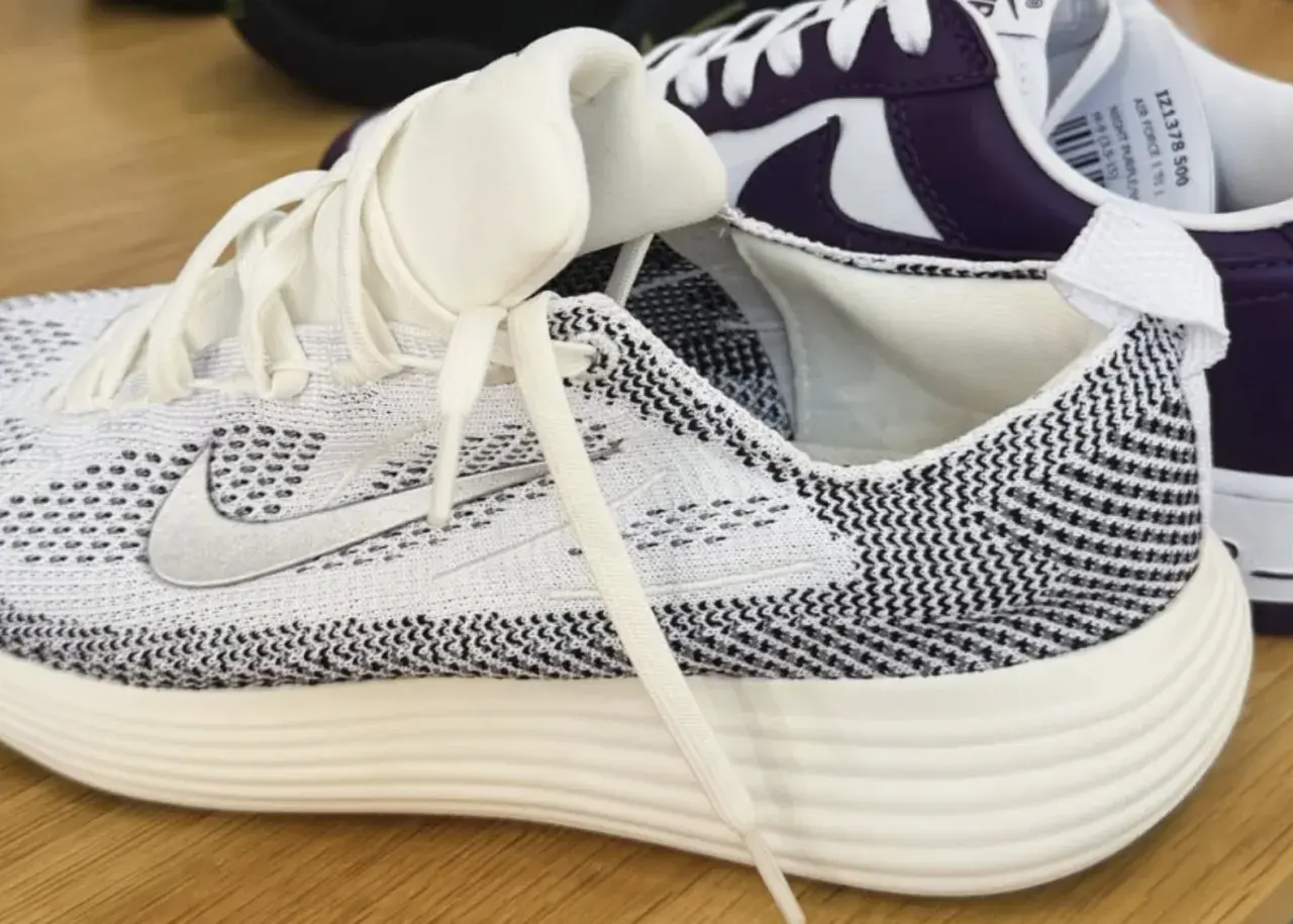 Weiße und schwarze **Shima Shima** Muster zieren diesen Laufschuh. Ein weiterer Schuh in Lila und Weiß ist im Hintergrund zu sehen.